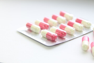 Pink-green pill capsules were placed on a white table.