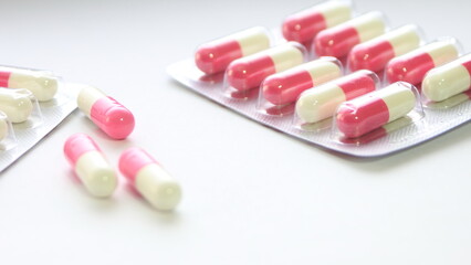 Pink-green pill capsules were placed on a white table.