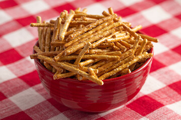 Bowl of Extra Thin Salted Stick Pretzels on a Red and White Table Cloth