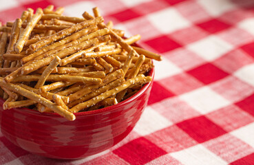 Bowl of Extra Thin Salted Stick Pretzels on a Red and White Table Cloth