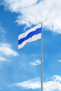 Russian white-blue-white anti-war protest flag is waving in front of blue sky and clouds.