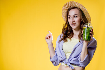 Beautiful young woman with plastic cup of fresh cocktail on yellow background