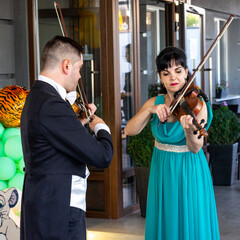 Violinists play violins at the entrance to the Philharmonic