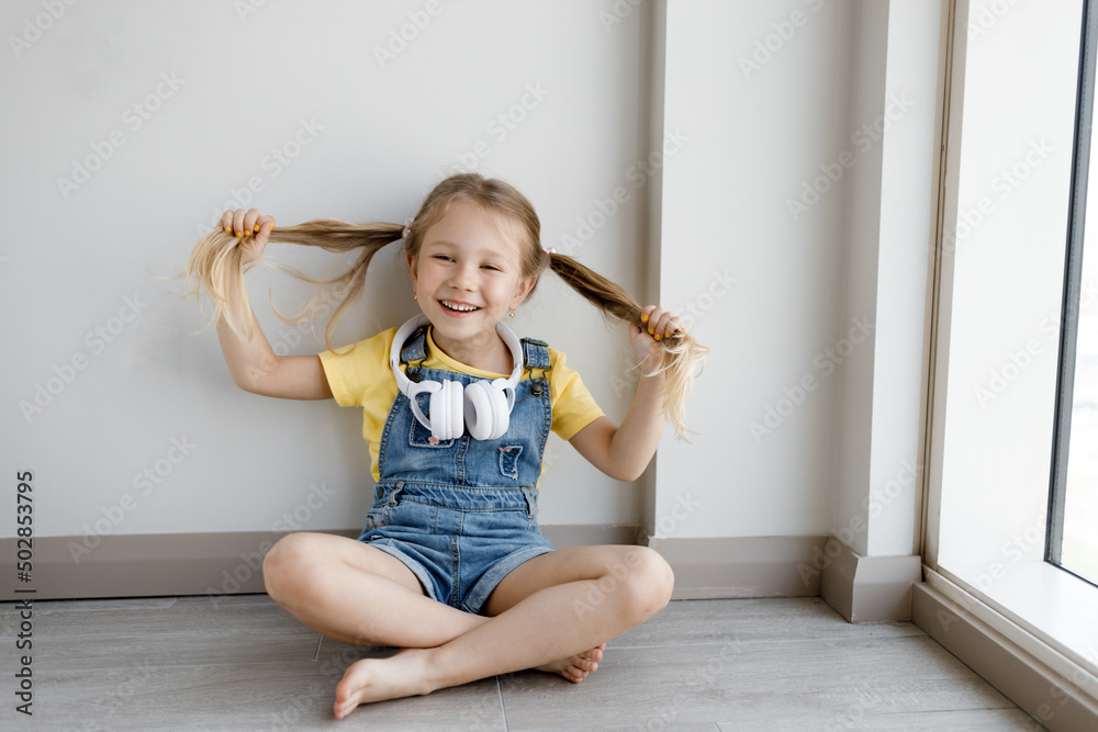 Wall mural cute little girl at home with headphones