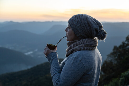 Woman drinking yerba mate drink on the morning on the top of a mountain, Rio Grande do Sul highlands, Brazil