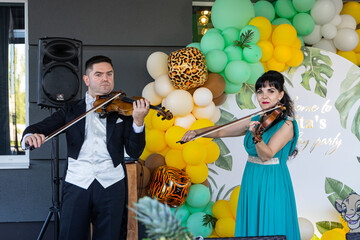 Violinists play violins on a background of colorful balloons