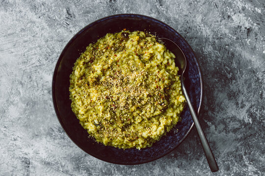 vegan zucchini and basil pesto risotto with cashew parmesan topping, healthy plant-based food