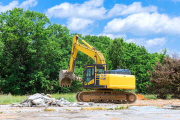 Backhoe excavator scoop loading from building in the construction debris