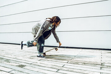 mujer morena con crespos con patineta divirtiéndose y haciendo deporte lista para patinar en la ciudad 
