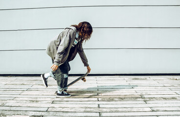 mujer morena con crespos con patineta divirti&eacute;ndose y haciendo deporte lista para patinar en la ciudad 