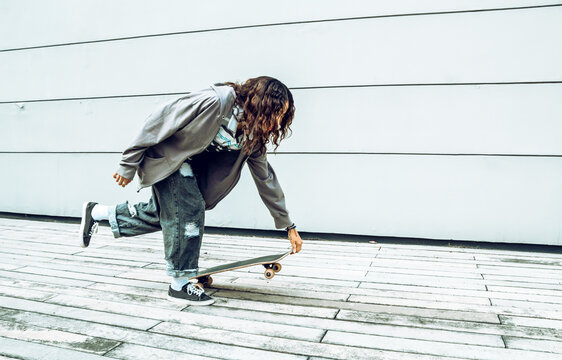 mujer morena con crespos con patineta divirti&eacute;ndose y haciendo deporte lista para patinar en la ciudad 