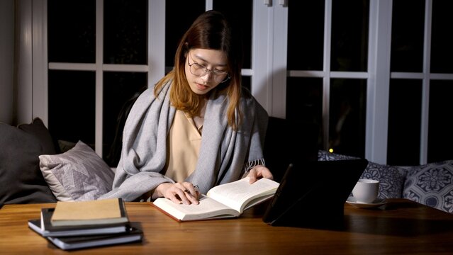 Asian Woman Reading Book And Research At The Night At Home.