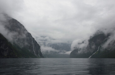 Cloudy Geirangerfjord in Norway. Grey sea and rocks, clouds on the water, clouds in the sky, clouds everywhere. The seven sisters and fiance waterfalls