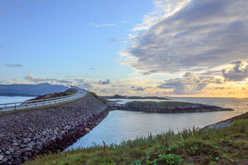 Evening at the Atlantic road in Norway. Blue and orange sunset sky with clouds, green grass, small rocky islands