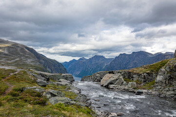 View of the landscape with the source of the Mardalsfossen waterfall in Norway. Grey sky with clouds, grey mossy rocks, white water of the mountain stream