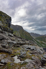 Gloomy Norwegian landscape: grey cloudy sky, dark mountain slopes, mossy rocks