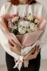 The girl is holding a delicate bouquet of flowers. Chrysanthemum, rose, tulip, spray rose