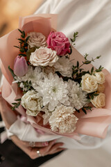 The girl is holding a delicate bouquet of flowers. Chrysanthemum, rose, tulip, spray rose