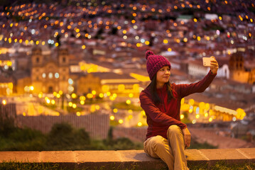 Turista sentada en el mirador tomándose un selfie hacia la plaza de Cuzco
