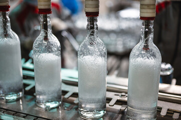Filling glass bottles with vodka drink on production line