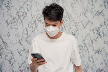 Man puts on a face mask using smartphone isolated on White background,pandemic and social...