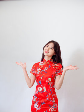 Portrait of young asian woman wearing traditional cheongsam qipao dress over isolated white background holding copyspace with two hands.