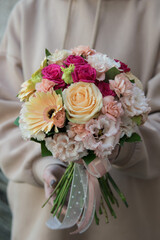 Bouquet for the bride in female hands. Flowers for the wedding. Peache and rose flowers. Gerbera, eustoma, roses.