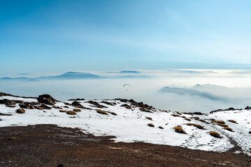 Horizontal shot of person paragliding on Provincia hill with mountains and fog in the background, Chile