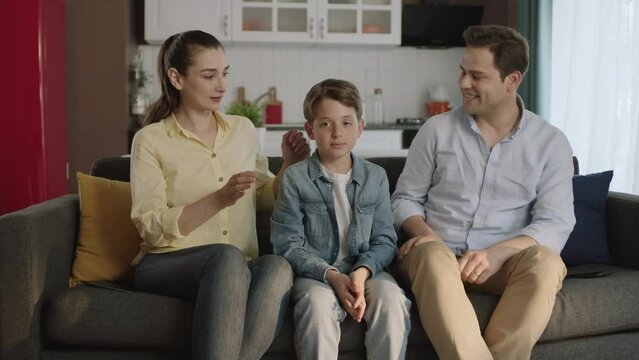 Young mother closes her son's eyes and surprises his father.Portrait of happy modern parents giving a soccer ball to their son as a birthday present. Birthday concept.