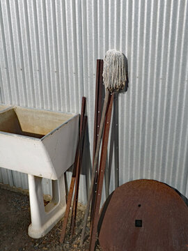 Old concrete laundry tub with mop and rusted metal. backgrounded on shiny galvanised corrugated iron wall. "Cleaning Spata"