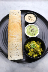 Crispy Masala dosa is a popular South Indian food item served with tomato chutney, coconut chutney, spicy potato masala, or aloo ki sabzi and sambar. Copy space. Crunchy Rice crepes.
