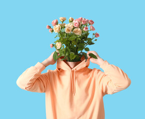 Man with bouquet of flowers instead of his head on blue background