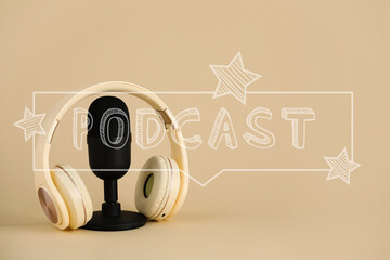 Microphone with headphones on beige background with word PODCAST