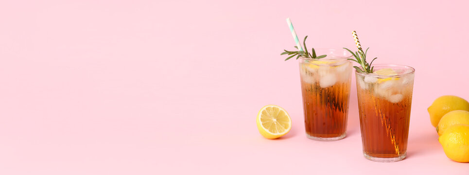 Glasses of tasty iced black tea with lemon on pink background with space for text