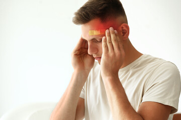 Man with medical patch on his forehead suffering from headache on white background