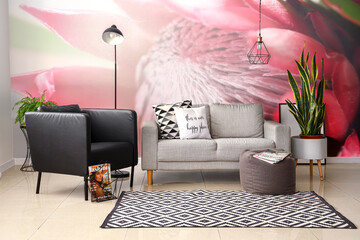 Interior of stylish living room with modern armchair and sofa near wall with printed flowers