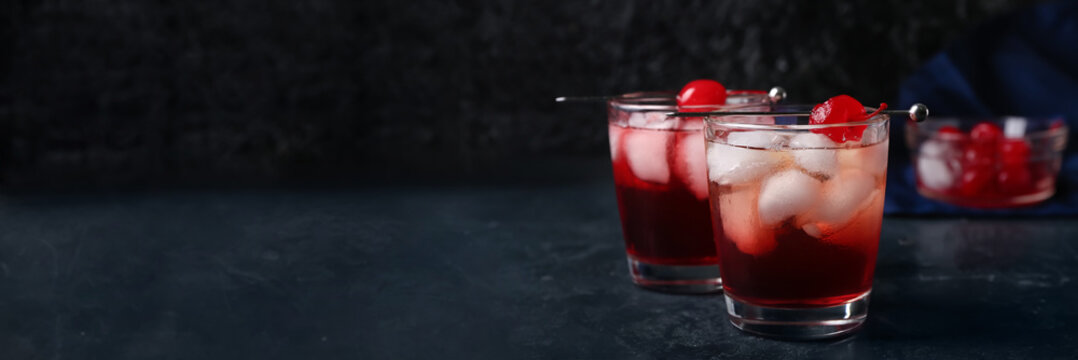 Glasses of delicious Manhattan cocktail on dark background with space for text