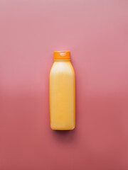 Top view of an empty orange plastic bottle for shampoo or lotion. Beauty concept for body or hair. Gradient pink background. Place for text. Copy space. Vertical