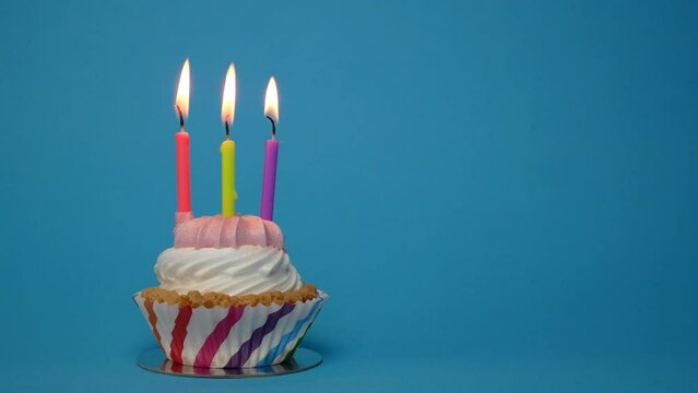 birthday cupcake with lit candle on blue background.Copy space. place for text