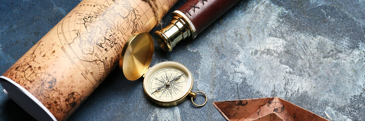 Vintage compass, spyglass, paper boat and world map on grunge background. Travel concept