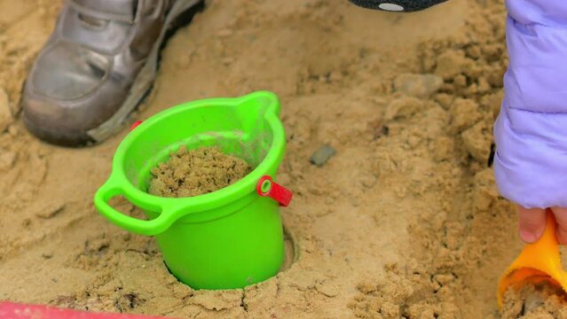 Close-up, a child digs sand, picks it up in a shovel and puts it in a bucket, children's games in the fresh air.