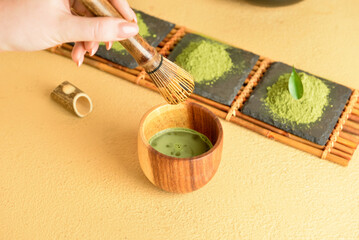 Woman preparing tasty matcha tea on color background, closeup