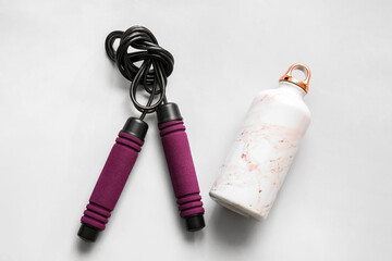 Bottle and skipping rope on white background