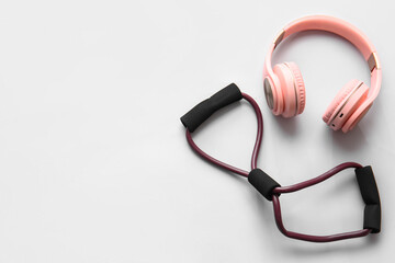 Fitness expander and stylish headphones on white background