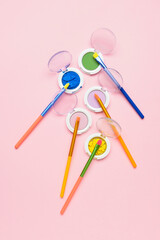 Colorful makeup brushes with eyeshadows on pink background