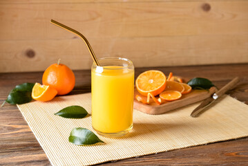 Glass of fresh tangerine juice on wooden background