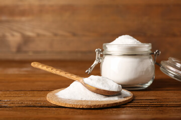 Pile of baking soda and spoon on wooden background