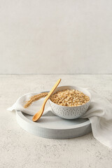 Bowl of raw oatmeal and spoon on light background - obrazy, fototapety, plakaty