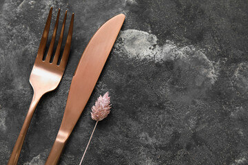 Golden cutlery and floral decor on grunge background