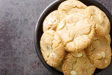 White chocolate biscuit cookies and macadamia nuts in the plate on the table close-up. Horizontal top view from above